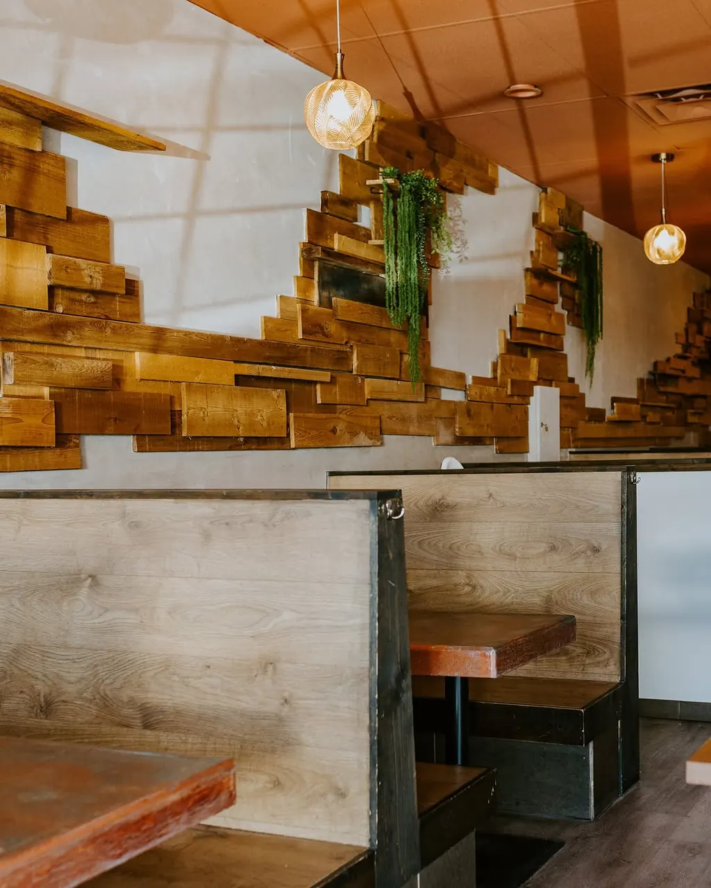 Booth seating at Lupita Mexican Cantina under a reclaimed-wood wall and hanging pendant lights